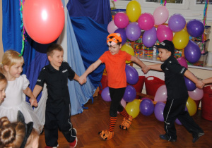 chłopcy przebrani za policjantów i tygryska tańczą w kole